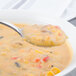 A Walco Saville stainless steel bouillon spoon in a bowl of soup.