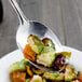 A Walco stainless steel tablespoon full of food on a plate.
