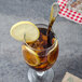 A glass of iced tea with lemon slices and a Walco Meteor stainless steel iced tea spoon.