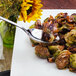 A Walco Lisbon stainless steel serving spoon with food on a plate.