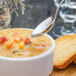 A Walco Bosa Nova stainless steel bouillon spoon in a bowl of soup.