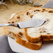 A close up of a Walco stainless steel butter knife with a slice of bread on a plate.