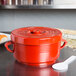 A red Thunder Group rice container with a lid on a table with a white spoon on top.