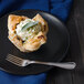 A pastry with cream on top and a Walco Marcie dinner fork on a black plate.