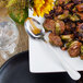 A plate of food with a Walco Marcie stainless steel serving spoon next to a glass of water.