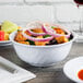 A close up of a white Thunder Group melamine swirl bowl filled with food.