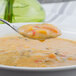A Walco Barony stainless steel bouillon spoon holding soup over a bowl.