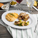 A white oval platter with food including macaroni and brussels sprouts.