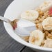 A Walco stainless steel teaspoon in a bowl of oatmeal with bananas and strawberries.