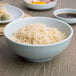 A close up of a bowl of rice in a Thunder Group Blue Jade melamine bowl.