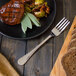 A Walco Marcie stainless steel table fork on a plate of food.