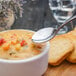 A Walco Marcie stainless steel bouillon spoon in a bowl of soup on a table.