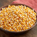 A bowl of Reist HI-POP organic mushroom popcorn kernels on a wooden table.