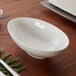 A Villeroy & Boch white bone porcelain bowl on a wood table.