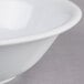 A close up of a white Thunder Group Imperial melamine deep bowl with a white rim.