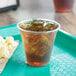 A Choice clear plastic cup filled with iced tea on a tray with popcorn.