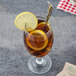 A glass of iced tea with lemon and a Walco stainless steel iced tea spoon.