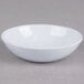 A white Thunder Group coupe sauce dish on a grey surface.