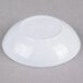 A white Thunder Group sauce dish on a gray surface.
