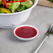 A bowl of salad with a fork and a Thunder Group white sauce dish filled with red sauce.