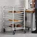 A metal half-height bun and sheet pan rack with four trays holding baked goods.