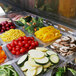 A Turbo Air sandwich prep table filled with trays of broccoli, carrots, tomatoes, and meat.