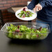 A woman holding a plate of salad with a Cambro clear rectangular ribbed bowl.