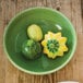 A bowl of green vegetables in a Tuxton Cilantro China bowl on a table.