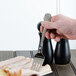 A hand holding a Walco stainless steel meat fork over sliced meat.