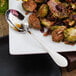 A plate of food with a Walco stainless steel serving spoon on it.