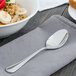 A Walco stainless steel teaspoon on a napkin next to a bowl of oatmeal.