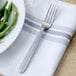 A Walco Maremma stainless steel dinner fork on a napkin next to a plate of green beans.