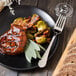 A plate of food with a Walco stainless steel dinner fork next to a glass of wine.