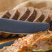 A Walco stainless steel European dinner knife cutting a piece of food on a plate.