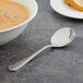 A Walco bouillon spoon in a bowl of soup on a table.