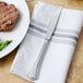 A Walco stainless steel table knife on a napkin next to a plate of food.