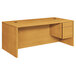 A HON harvest wood pedestal desk with a drawer.