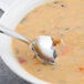 A Walco Maremma stainless steel bouillon spoon in a bowl of soup.