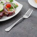 A Walco stainless steel salad fork next to a plate of salad.