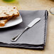 A plate with bread and a Walco stainless steel butter spreader on it.