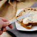 A person spreading butter on a piece of bread with a Walco stainless steel butter knife.