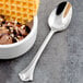 A spoon next to a bowl of chocolate ice cream with waffles.