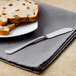 A Walco stainless steel butter spreader on a table with a plate of bread.