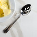 A Walco Ultra stainless steel pierced serving spoon with butter in a bowl.