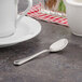 A Walco stainless steel demitasse spoon in a white cup on a saucer.