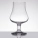 A close up of a Stolzle nosing glass with a small amount of liquid in it.