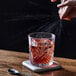 A person pouring a drink into an Arcoroc old fashioned glass on a table.