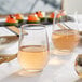 A table with Acopa tall stemless wine glasses filled with wine on it.