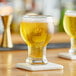 Two Acopa Select Craft Master beer glasses filled with beer on a wooden table.