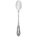 A close-up of a Walco stainless steel iced tea spoon with an ornate pattern.